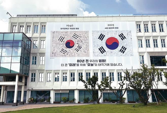 서울공예박물관이 광복 80주년을 기념하기 위해 시민과 독립유공자 후손 80명이 함께 만든 ‘서명문 태극기’를 지난 16일 제작해 건물 정면 오른쪽에 내걸었다. 왼쪽은 1946년 제작된 ‘한국광복군 서명문 태극기’(독립기념관 소장)다.