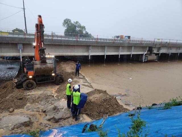 2023년 7월 15일 오송 미호강 미호천교 건설 공사 현장에서 시공사 관계자들이 장비를 이용해 임시제방 보강 작업을 하고 있다. 둑 유실로 궁평2지하차도에 물이 급격하게 들이닥치기 1시간 8분 전인 오전 7시 22분에 촬영된 사진이다. 사진 속 범람 위기의 강은 금강 제1 지류인 미호강이다. 환경부와 충북도가 작년 7월 미호천을 미호강으로 명칭을 변경, 고시했다. 감리단 제공