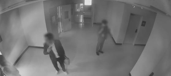 지난해 11월 8일 전주지검 구치감 대기실 앞 복도에서 A씨(가운데)가 왼손에 피의자 B씨 짐이 담긴 종이 가방, 오른손엔 휴대전화를 든 채 B씨(왼쪽)와 함께 인권보호관 상담실로 이동하고 있다. 사진은 CCTV 영상 캡처. 당시 현장에 있던 전북경찰청 형사기동대 직원들은 모두 법정에서 "대기실에서 일어난 일을 직접 목격하지 못했다"고 진술했다. 사진 A씨