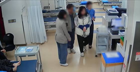 지난해 11월 4일 전북 전주 한 병원 응급실에서 A씨(왼쪽 두 번째) 등 전주 완산경찰서 소속 남녀 수사관 3명이 치료를 마친 피의자 B씨(흰색 조끼)를 데리고 전주 덕진경찰서 유치장으로 향하고 있다. B씨는 "어깨 골절 수술을 받은 지 얼마 안 돼 통증이 심하다"고 했지만, 진즉 완치된 것으로 조사됐다. 이날 병원에서 B씨는 A씨에게 부축해 달라며 A씨 손을 잡거나 어깨에 기댔다는 게 A씨 변호인 측 주장이다. 사진 A씨