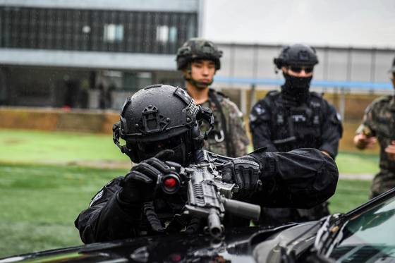 차량 근접전술 사격(VCQB) 훈련에서 차량에 몸을 숨겨 사격하고 있는 공군 장병. 육군 장병이 뒤에서 이를 지켜보고 있다. 공군 17전비