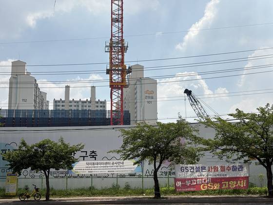 A data center under construction in Ilsan, Gyeonggi Province, operated by Magna PFV, is seen on July 28. Protest banners tied to roadside trees were put up by a local opposition committee. [LEE JAE-LIM]