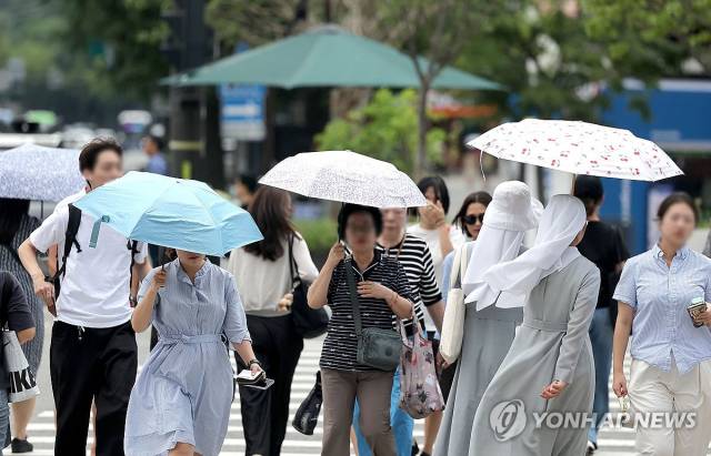 서울의 한 낮 기온이 38도를 오르내리면서 시민들이 저마다 양산을 쓴 채 걸어가고 있다. 연합뉴스