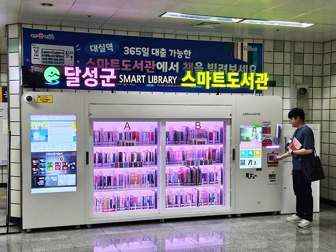 대구도시철도 2호선 대실역 지하 1층 중앙로비에 설치된 '스마트도서관'에서 한 시민이 도서를 대출하고 있다.<달성군 제공>