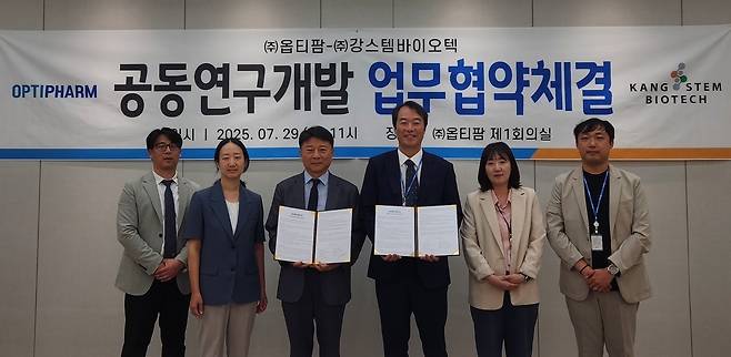 나종천 강스템바이오텍 대표(왼쪽에서 세 번째)와 김현일 옵티팜 대표(왼쪽에서 네 번째), 각 기업 관계자가 공동연구개발 업무협약 체결식에서 기념사진을 찍고 있다.(강스템바이오텍 제공)/뉴스1