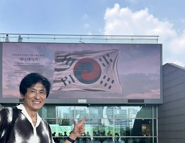양방언 씨가 지난달 28일 국립중앙박물관 열린마당 전광판의 데니 태극기 앞에서 포즈를 취했다.  엔돌프뮤직 제공