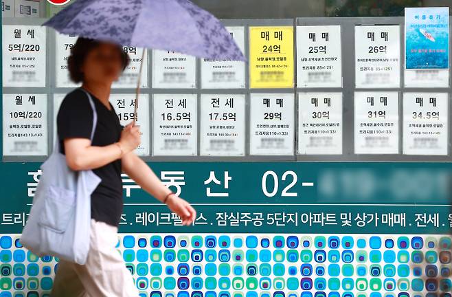 서울의 한 공인중개사무소 앞을 한 시민이 지나고 있다.&nbsp;최근 부동산 시장에서는 신고가 거래는 이어지지만 실제 매수 문의는 급감하며 거래 공백 현상이 나타나고 있다. 연합뉴스
