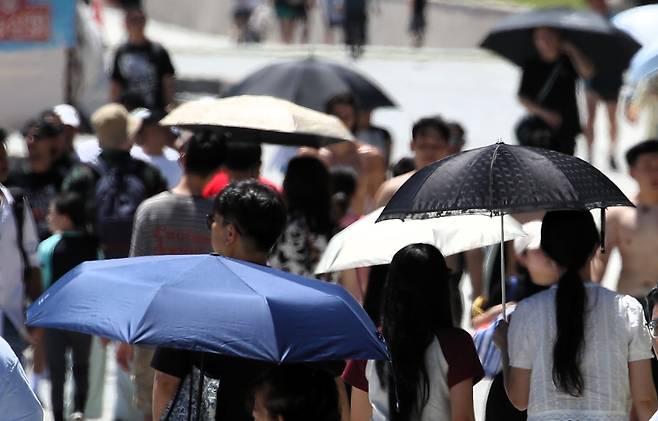 지난달 27일 오후 부산 해운대해수욕장에서 시민들이 양산을 쓰고 걷고 있다. /김동환 기자