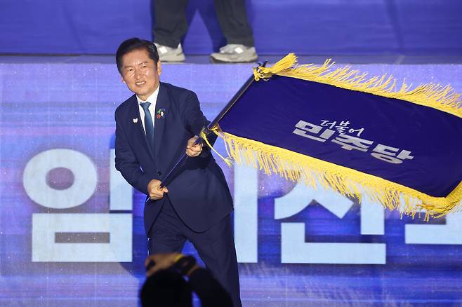 더불어민주당 정청래 신임 당대표가 2일 고양 킨텍스에서 열린 전국당원대회에서 김병기 당대표 직무대행 겸 원내대표로부터 받은 당기를 흔들고 있다./연합뉴스