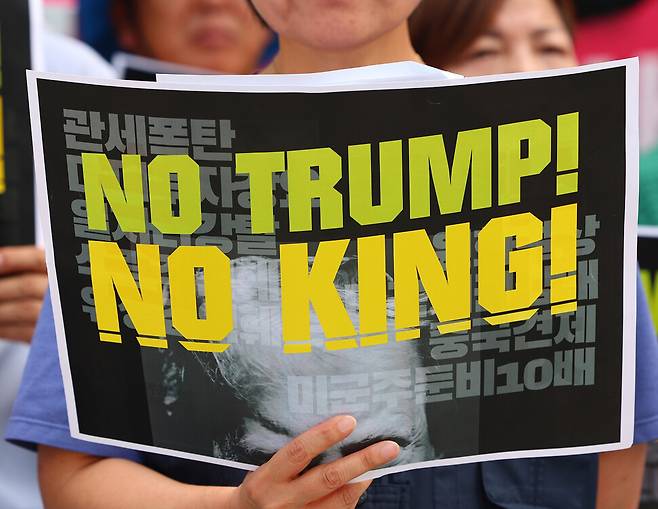 한-미 관세 협상이 타결된 2025년 7월31일 서울 광화문 미국대사관 앞에서 ‘트럼프위협저지공동행동’ 등의 주최로 열린 기자회견에 참석한 활동가가 도널드 트럼프 미국 대통령을 비판하는 손팻말을 들고 있다. 연합뉴스