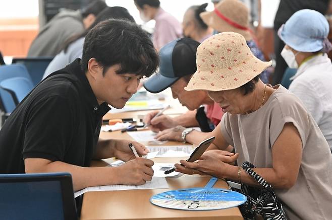 민생회복 소비쿠폰 1차 신청이 시작된 지난 21일 오전 광주 북구 두암3동 행정복지센터에서 주민들이 선불카드 신청 상담을 하고 있다. 뉴시스