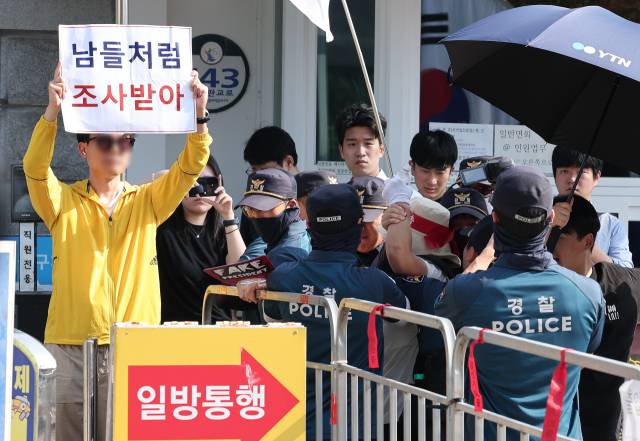 김건희 여사의 각종 의혹을 수사하는 김건희 특검팀(특별검사 민중기)이 윤석열 전 대통령에 대한 체포영장 집행에 나선 1일 오전 경기도 의왕 서울구치소에서 윤 전 대통령 지지자가 '남들처럼 조사받아' 라는 피켓을 든 한 시민에게 달려가자 경찰이 저지하고 있다. 뉴스1