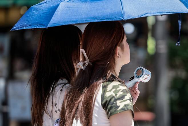 일요일인 3일은 무더위 속 오후부터 전국에 강한비가 내릴 전망이다. 사진은 서울시내 한 거리에서 양산을 쓴 여행객들이 손선풍기를 들고 이동하던 모습. /사진=뉴시스