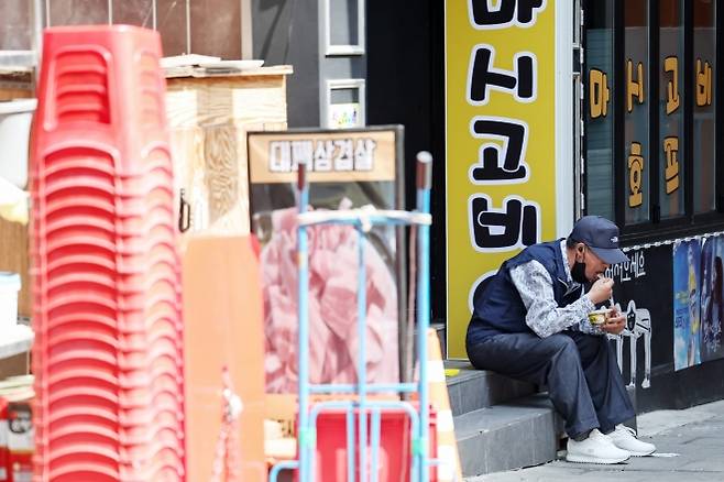 서울 종로구 탑골공원 인근 골목에서 한 어르신이 간편 죽으로 끼니를 때우고 있다. 뉴스1