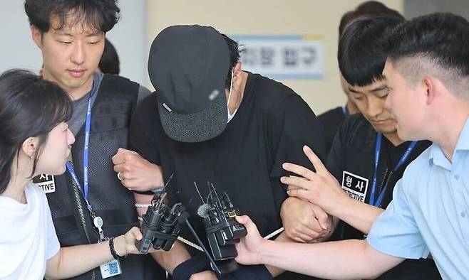 울산 북구의 한 주차장에서 20대 여성에게 흉기를 휘둘러 살해하려 한 혐의(살인미수)로 경찰에 체포된 ㄱ씨가 지난달 30일 울산지방법원의 구속 전 피의자심문(영장실질심사)에 출석하기 위해 호송차로 이동하고 있다. 연합뉴스