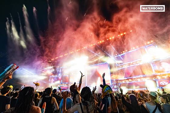 워터밤의 야외 무대 현장. 조명과 물줄기, 관객들의 환호성 등이 어우러진 장면이다. 메이드온