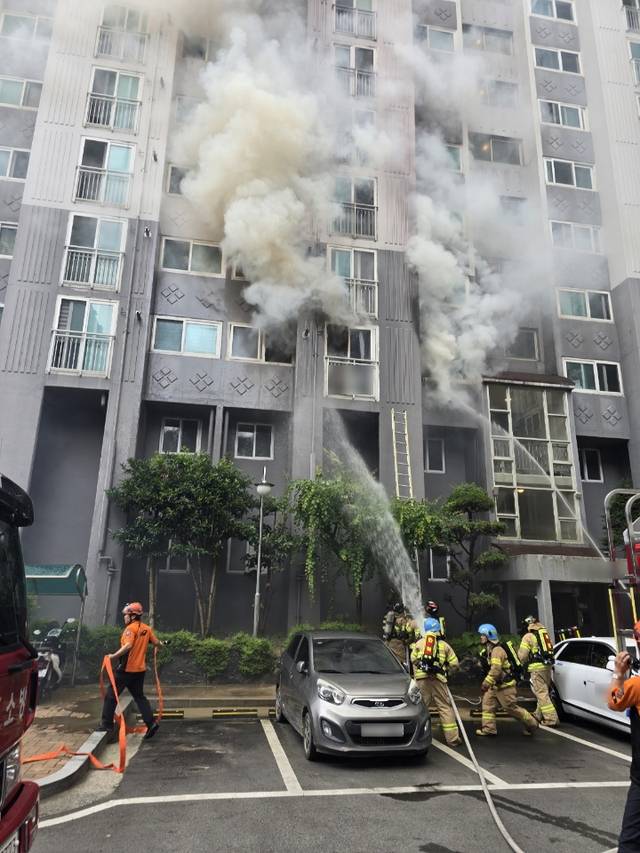 지난달 13일 낮 불이 난 부산 북구 만덕동 아파트 밖에서 소방대원들이 불길을 잡고 있다. 이 사고로 80대 노모와 50대 아들이 숨졌다. 부산경찰청 제공