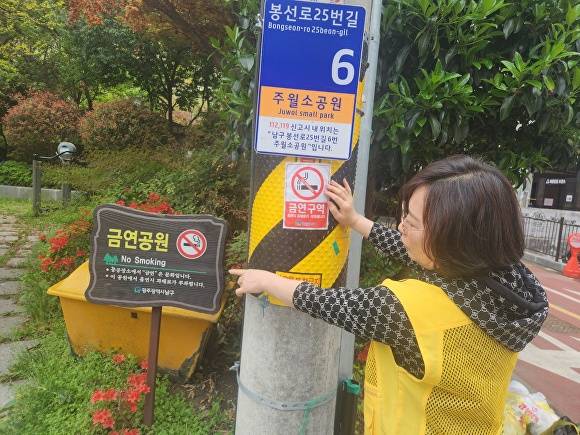 광주 남구 관계자가 금연표지판을 가리키고 있다. [사진=광주 남구]