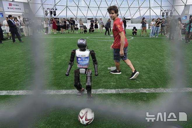 [베이징=AP/뉴시스] 4일(현지 시간) 중국 베이징에서 열리는 '2025 세계 휴머노이드 로봇 게임'을 앞두고 언론 공개 행사가 열린 가운데 부스터 휴머노이드 로봇들이 축구 시범 경기로 기술을 선보이고 있다. 오는 14일부터 17일까지 열리는 이 행사에는 축구를 비롯해 달리기, 격투, 댄스 등 실제 사람의 경기와 유사한 종목이 포함된 것으로 알려졌다. 2025.08.04.