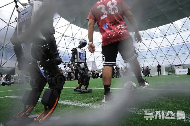 [베이징=AP/뉴시스] 4일(현지 시간) 중국 베이징에서 '2025 세계 휴머노이드 로봇 게임'을 앞두고 언론 공개 행사가 열린 가운데 부스터 휴머노이드 로봇들이 축구 시범 경기로 기술을 선보이고 있다. 오는 14일부터 17일까지 열리는 이 행사에는 축구를 비롯해 달리기, 격투, 댄스 등 실제 사람의 경기와 유사한 종목이 포함된 것으로 알려졌다. 2025.08.05.