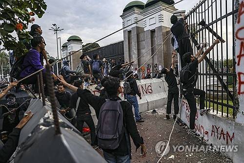 2025년 3월 20일, 인도네시아 자카르타에서 군법 개정에 반대하는 시위대가 국회의사당 울타리를 허물려고 하고 있다. [EPA=연합뉴스]