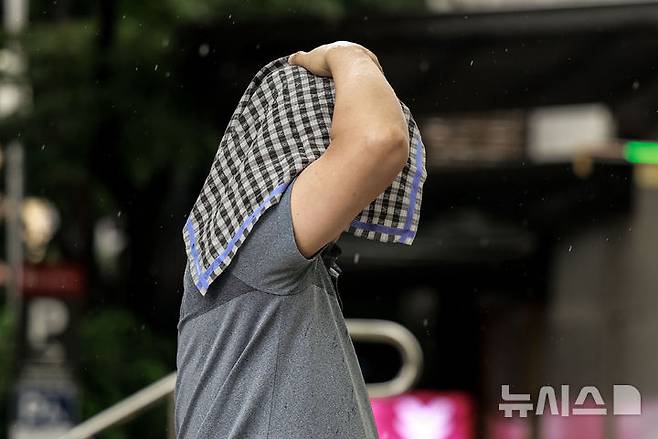 [서울=뉴시스] 정병혁 기자 = 소나기가 쏟아진 8일 서울 중구 청계천 일대에서 손수건으로 머리를 가린 시민이 이동하고 있다. 2025.08.08. jhope@newsis.com