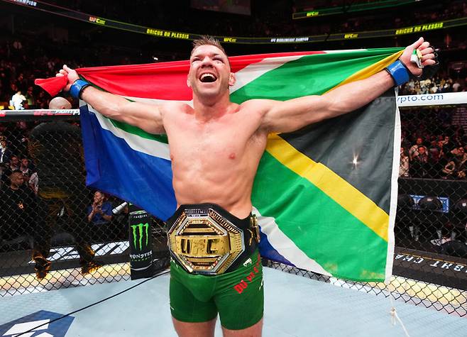 UFC 297에서 션 스틀릭랜드를  물리치고 챔피언에 오른 드리커스 두 플레시스가 국기를 들고 기뻐하고 있다. 사진 | UFC