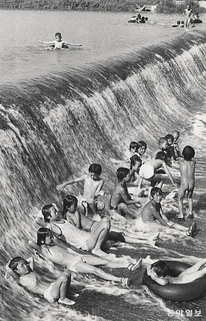 자연풀- 방학을 맞은 시골 어린이들이 연일 계속되는 불볕더위를 피해 봇둑아래서 시원한 물을 맞고 있다. 도시의 콩사물 시루같은 풀장이 전혀 부럽지 않은 봇둑아래서는 시원한 봇물이 등을 두드려주어 좋고 그동안 자주 만나지 못했던 친구들을 만날 수 있어 더욱 좋다. 방학숙제 걱정도 없진 않지만 봇둑에 나온 어린이들은 올 여름내내 이곳에서만 놀고싶다. 보은=김녕만 기자. 1981년 7월 30일. 동아일보 DB