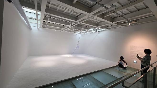 [사진=박현주 미술전문기자' 부지현의 'Solid Sea'. 폐집어등과 소금, 푸른빛으로 구성된 공간 설치작품이다. 바닥에 펼쳐진 소금 위로 낡은 집어등이 떠 있다. 과거 밤바다를 밝히며 물고기를 유인하는 데 사용됐던 집어등은 어민들의 노동과 생존을 상징하는 도구였다.  *재판매 및 DB 금지