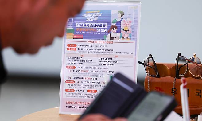 이재명 정부의 첫 대규모 경기 부양책인 '민생회복 소비쿠폰' 신청이 시작된 지난 7월 21일 서울 종로구 광화문우체국에 관련 안내문이 비치돼 있다. 연합뉴스