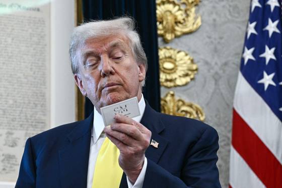 도널드 트럼프 미국 대통령이 지난 7일(현지시간) 워싱턴DC 백악관에서 최근 발표된 부진한 고용지표에 대해 반박하는 연설 도중 회견에 참석한 경제학자 스티븐 무어의 명함을 바라보고 있다. AFP=연합뉴스