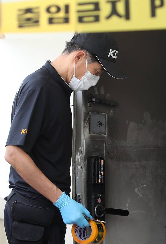 지난 10일 오후 경찰이 아파트 주변을 통제한 뒤 현장감식을 진행하고 있다. 불이 난 아파트 현관 출입문 잠금장치(도어락)에 건전지 일부가 빠져 있다. 뉴스1