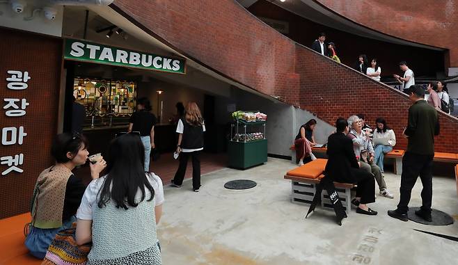 Customers are seen at the Gwangjang Market branch of Starbucks in downtown Seoul on May 29. The location blends the market’s history into a retro interior as part of a series of special-concept stores. Starbucks Korea ended 2024 with 2,009 outlets, moving past Japan for the first time and placing behind only the US and China in store numbers. (Starbucks Korea)