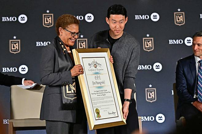 Son Heung-min, right, and Los Angeles mayor Karen Bass hold a plaque during a press conference as he joins Los Angeles FC at BMO Stadium’s Field Club in Los Angeles on Aug. 6. [AFP/YONHAP]