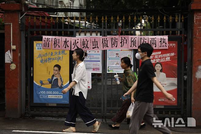 [광저우=AP/뉴시스] 중국 남부 광둥성에서 치쿤구니야열 확산세가 한풀 꺾인 양상을 보이고 있다. 사진은 지난 6일 광둥성 광저우의 도심에서 행인들이 치쿤구니야열 확산을 막아야 한다는 구호가 걸린 길거리를 오가는 모습. 2025.08.11