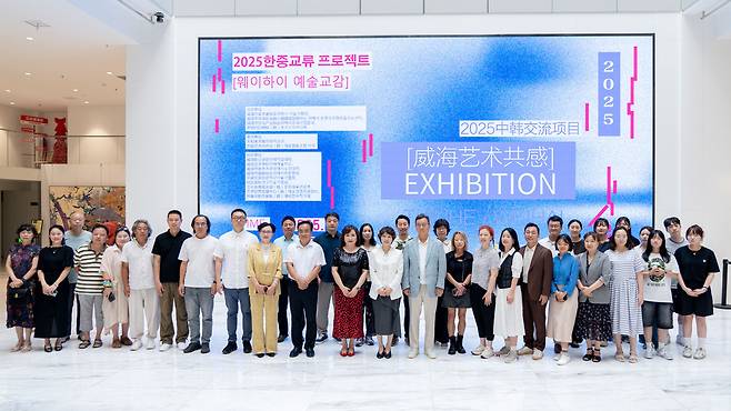 ▲ 2025 한중교류 프로젝트 'WeiHai 예술교감' 전시가 열린 중국 웨이하이 천화미술관에서 권일순 대표와 참여 작가들이 기념사진을 촬영하고 있다./사진제공=예술협동조합 이루