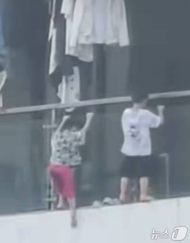 구이저우성 구이양시의 한 고층 아파트에 어린아이 2명이 매달려 있다. (지무신문 갈무리)