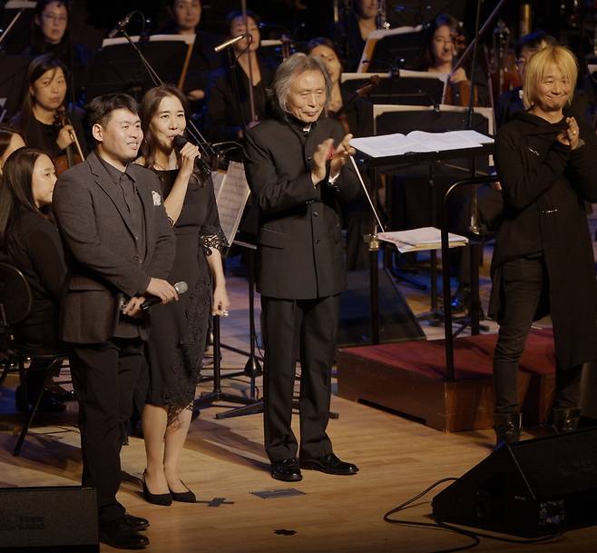 광복절 80주년 시네마틱 콘서트 '네버포가튼 815: 빛의 부활'을 여는 음악감독 마이클 최(앞줄 맨왼쪽)가 앞선 공연에서 무대에 올라 인사하고 있다. 그는 지난 2023년부터 전쟁과 평화에 관한 역사 의식을 다지는 공연을 매년 개최 중이다.