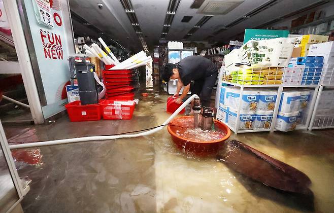 집중호우가 내린 13일 인천시 서구 가정동 정서진중앙시장 한 상가가 침수돼 상인이 배수 작업을 하고 있다. 연합뉴스