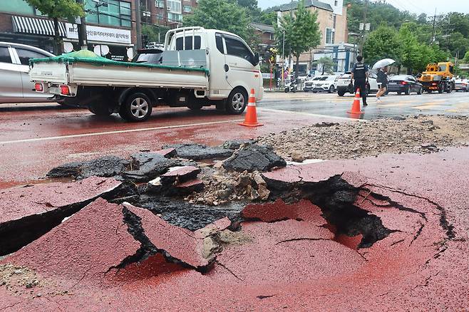 서울시 종로구 한 도로에서 폭우로 땅꺼짐 현상이 발생해 경찰이 교통을 통제하고 있다. 연합뉴스