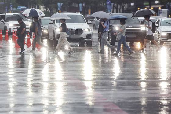 Commuters hurry across Gwanghwamun Intersection in Jongno District, central Seoul, on Aug. 13 as a heavy rain advisory is in effect for the capital. [NEWS1]