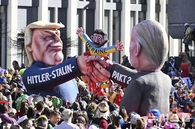 [뒤셀도르프=AP/뉴시스] 3일(현지 시간) 독일 뒤셀도르프에서 열린 전통 로즈 먼데이(로젠 몬탁) 퍼레이드에서 도널드 트럼프(왼쪽) 미국 대통령과 블라디미르 푸틴 러시아 대통령이 볼로디미르 젤렌스키 대통령의 우크라이나를 쥐어짜며 협정을 강행하는 모습을 형상화한 풍자 조형물이 전시되고 있다. 알래스카 미러정상회담을 앞두고 유럽에서 트럼프가 푸틴에게  놀아날 것이라는 우려가 커지고 있다. 2025.08.13.