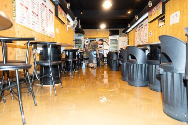 13일 서울 은평구 연신내역 인근 가게에서 상인이 폭우로 들이닥친 흙탕물을 청소하고 있다. 뉴스1