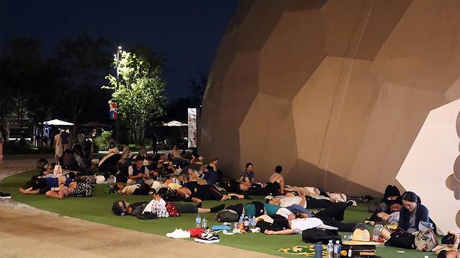 오사카 엑스포 박람회장에 누워 있는 관람객들 [연합뉴스/지지·EPA 제공]