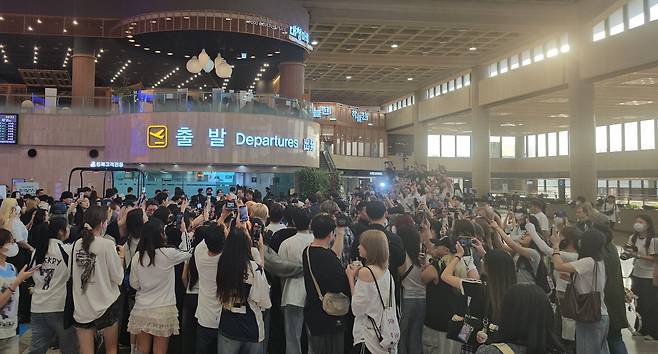 Fans and reporters are seen gathered outside the security check gate while boy band AHOF enters the gate at the Gimpo International Airport in western Seoul on Aug. 8 [SHIN HA-NEE]