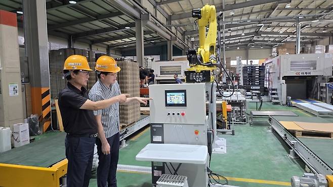 (사진 왼쪽) 한현수 대세물산 대표이사와 김정호 삼성전자 ESG&스마트공장지원센터 위원이 삼성 스마트공장 지원사업을 통해 설치 중인 로봇의 작업을 살펴보고 있다. [시진 = 삼성전자]