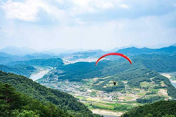 두산 활공장에서 이륙한 패러글라이더. 아래 덕천리가 보인다. 뒤에 보이는 채석장은 성신양회 단양공장이다.