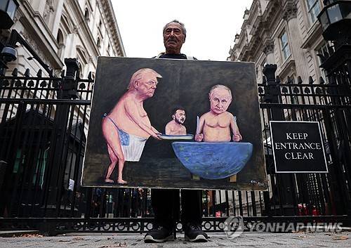 영국 총리실 근처에서 트럼프 대통령과 푸틴 대통령 풍자 작품을 들고 있는 예술가. [EPA 연합뉴스 자료사진. 재판매 및 DB 금지]