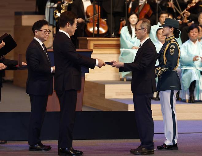 이재명 대통령이 15일 서울 종로구 세종문화회관에서 열린 제80주년 광복절 경축식에서 고(故) 이은숙 선생의 외손자 김종민 씨에게 건국훈장 애족장 훈장증을 전달하고 있다. 2025.08.15. 서울=뉴시스