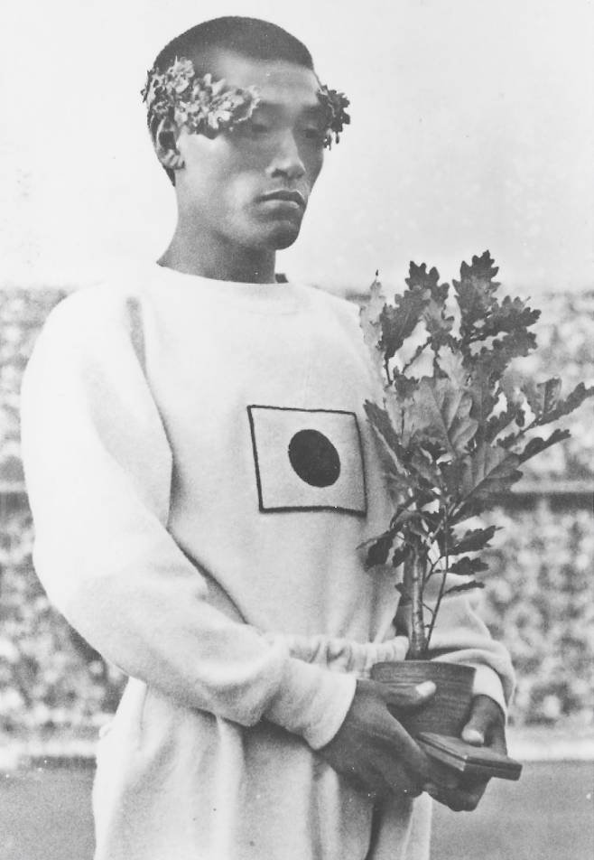 Son Kee-chung stands on the podium wearing the Japanese flag after winning gold in the marathon at the 1936 Berlin Olympics. [JOONGANG ILBO]